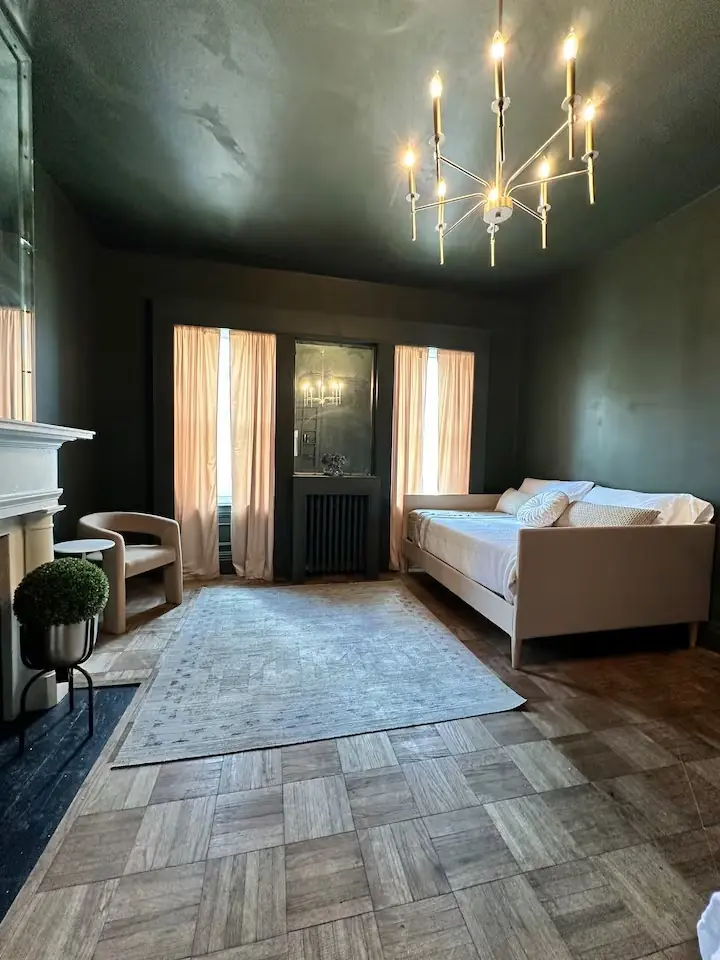 Bedroom with dark green walls and chandelier